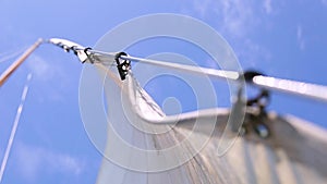 Sail boat navigating in the ocean sunny day showing the wooden parts and closeup of the sail of a wooden antique