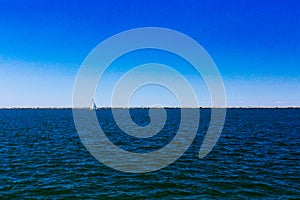 Sail boat over Lake Erie under blue sky, in Cleveland, USA