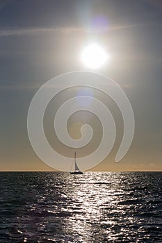 Sail boat silhouetted in the setting sun over the ocean in Mexico