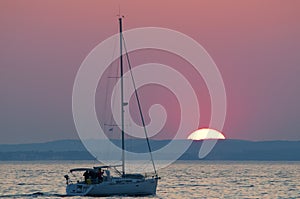 Sail boat and sunset on the horizon above sea