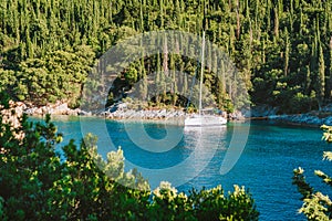 Sail boat yacht moored in the bay of Foki beach surrounded by cypress trees, Fiskardo, Cefalonia, Ionian, Greece