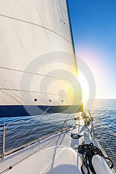 Sail boat yacht with set up sails gliding in open sea with sun