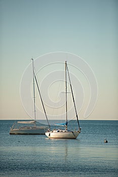 Sail boats anchored on a calm sea in late afternoon