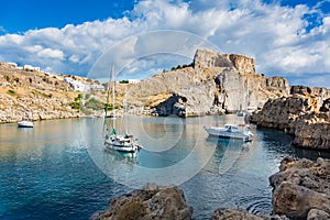 Sail boats in St. PaulÂ´s bay, cloudy blue sky, Lindos acropolis