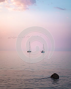 Sail boats at sunset over a glass-like ocean and a colorful sky