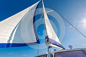 Sail of a sailing boat against sky with sun rays