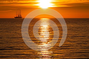 Sail ship silhouette at sea and sun