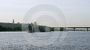 Sailboat and barge float on the summer Dnieper river in the Kiev city.