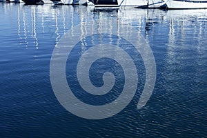 Sailboat blurred mast reflexion on the marina