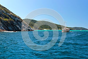 ARRAIAL DO CABO, RIO DE JANEIRO, BRAZIL- MARCH 21, 2016: Sailboat and a boat over a green and clear waters near a coast.