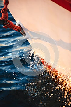 Sailboat bow cutting through the water, forward, sail and nautical rope yacht detail. Yachting, marine background