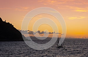 Sailboat on the coast of the city of Donostia with the last rays of the sun at sunset, Cantabrico Sea.