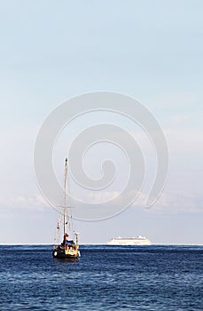 A sailboat and a cruise ship in the ocean
