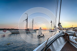 Sailboat Dingy Sails Between Wooden Boats at Sunset