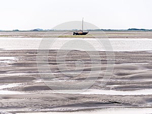 Sailboat dried out on sandflats of tidal sea Waddensea near Boschplaat, Terschelling, Netherlands photo