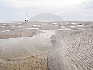 Sailboat dried out on sandflats of tidal sea Waddensea near Boschplaat, Terschelling, Netherlands photo