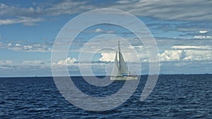 Sailboat floating on the sea. Coastline in background