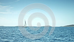 Sailboat floating on the sea. Coastline in background