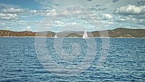 Sailboat floating on the sea. Coastline in background