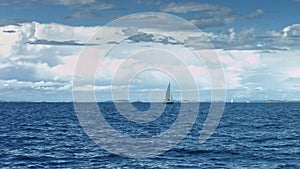 Sailboat floating on the sea. Coastline in background