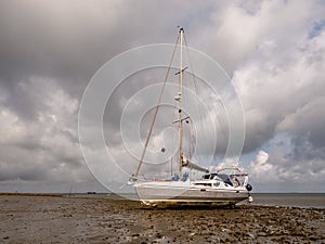 Sailboat grounded on mudflat at low tide of Wadden Sea east of Hooge Hallig, North Frisia, Germany