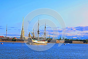 Sailboat with lowered sails moored near the shore of the Peter and Paul fortress in St. Petersburg