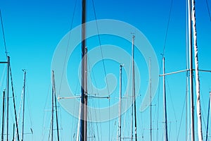 Sailboat masts in harbor against blue sky