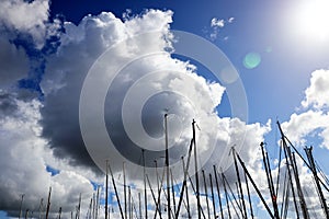 Sailboat masts under clouds - sunny day