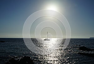 Sailboat on the Mediterranean Sea in the rays of the setting sun. Cirkewwa, Mellieha, Malta