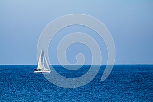Sailboat in the middle of a sea and under a blue sky