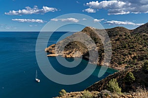sailboat moored in a bay of the Serra Gelada Natural Park with the Albir Lighthouse in the background