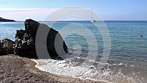 Sailboat moored next to the rocky and sandy shoreline. Foreland