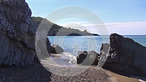 Sailboat moored next to the rocky and sandy shoreline. Foreland