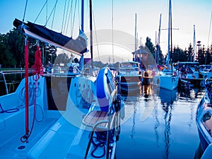 Sailboat moored on wooden jetty in the port at the evening time, view on sailing yacht deck with rigging