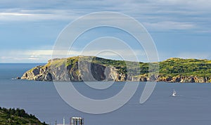 Sailboat navigates near Twillingate cliffs, seascape, landscape, Newfoundland, Atlantic Canada.