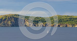 Sailboat navigates near Twillingate cliffs, seascape, landscape, Newfoundland, Atlantic Canada.