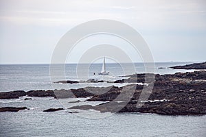 Sailboat near Oarweed Cove along the rocky coast of Maine in Ogunquit