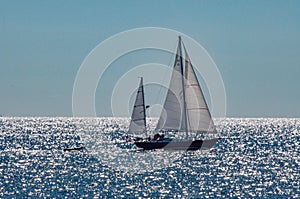 Sailboat on ocean backlit with sun shinning