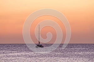 Sailboat on the ocean near the beach at sunset