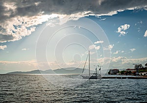 A sailboat in Pagasetic gulf. Dark clouds in blue sky. In Agria, Greece.