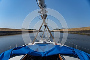 Sailboat passing by channel waterway or river. Concept of travel, adventure and vacation.