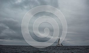 Sailboat sailing in the sea under the dark cloudy sky