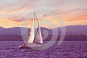 Sailboat sails near shore of Bay of Kotor at sunset. Montenegro. Travel concept