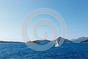 Sailboat sails past the coast of Montenegro to the Mamula island