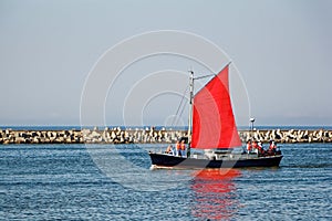 Sailboat with scarlet sails and sailors on board