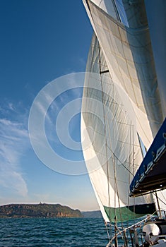 Sailboat at Sea Under Full Sail with Landfall in the distance.