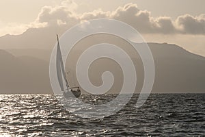 Sailboat on a stormy sea against the rocky shore photo