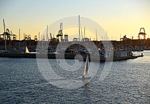 Sailboat on sunset in harbour. Sailing on sea on sailboat on the waves.