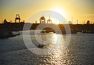 Sailboat on sunset in harbour. Sailing on sea on sailboat on the waves.