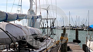 Sailboat tied to the dock in a marina in Rockport, Texas, in close up of rigging, with gentle motion of the boat as it bobs and